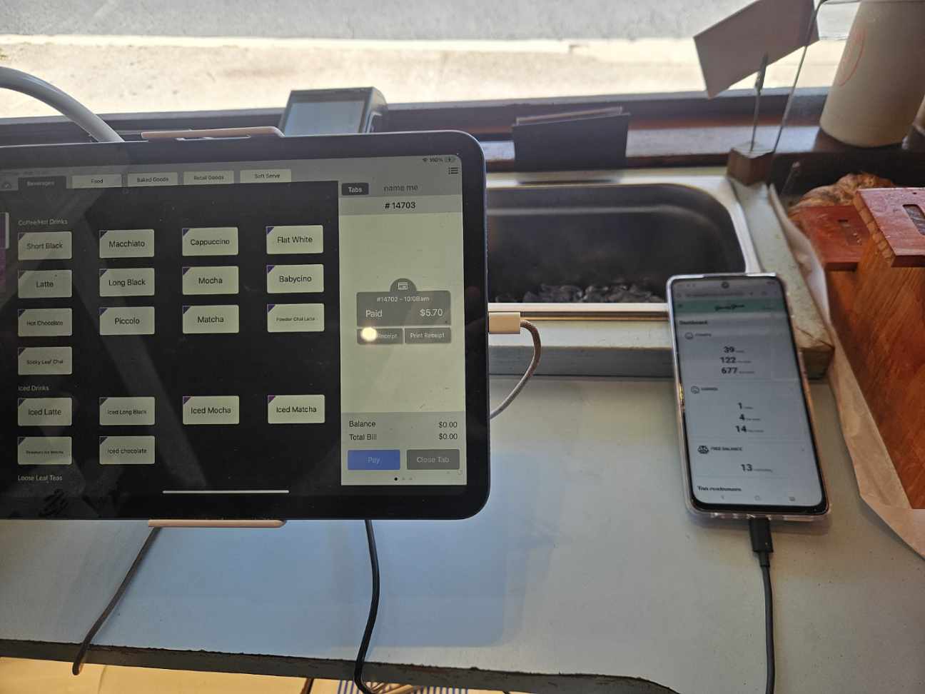 Bennett St Dairy's POS iPad next to a phone showing the merchant loyalty dashboard